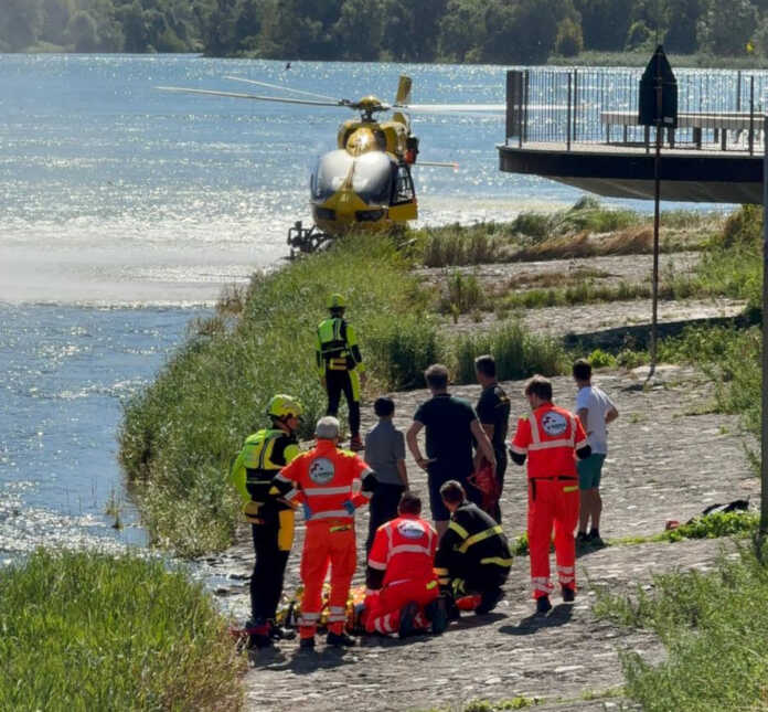 Olginate salvataggio uomo canoa diga 2025 (2) L'intervento dei soccorsi con le prime cure prestate al 66enne. Dietro l'elisoccorso giunto da Bergamo